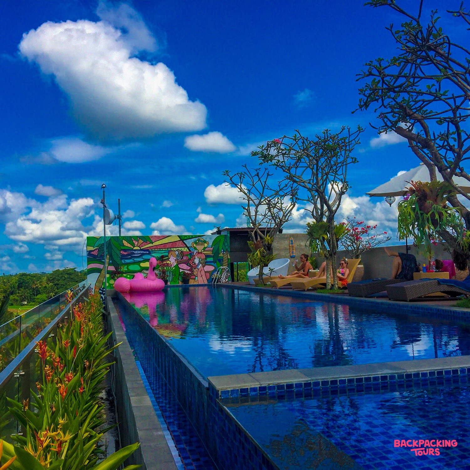 Relaxing rooftop swimming pool in Ubud, Bali, with lounge chairs and a pink flamingo float.