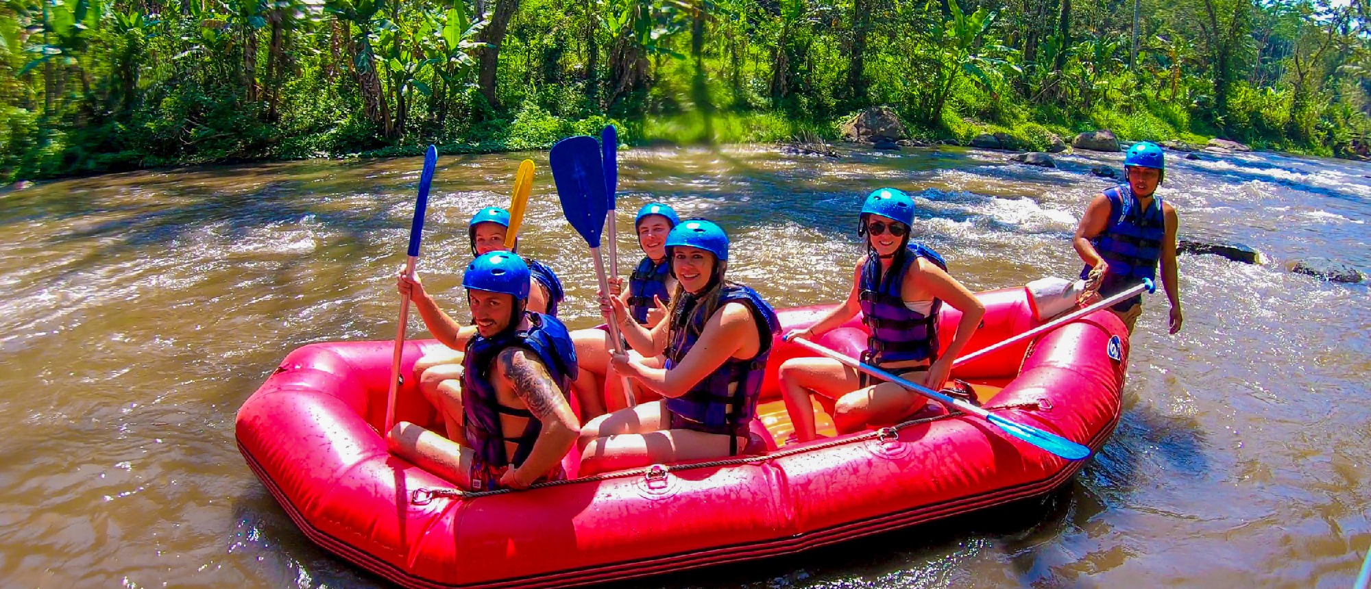 Group paddling raft down river rapids near Ubud