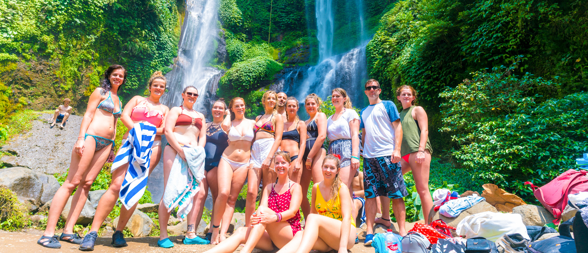 Backpacking group posing on rocks in front of a waterfall