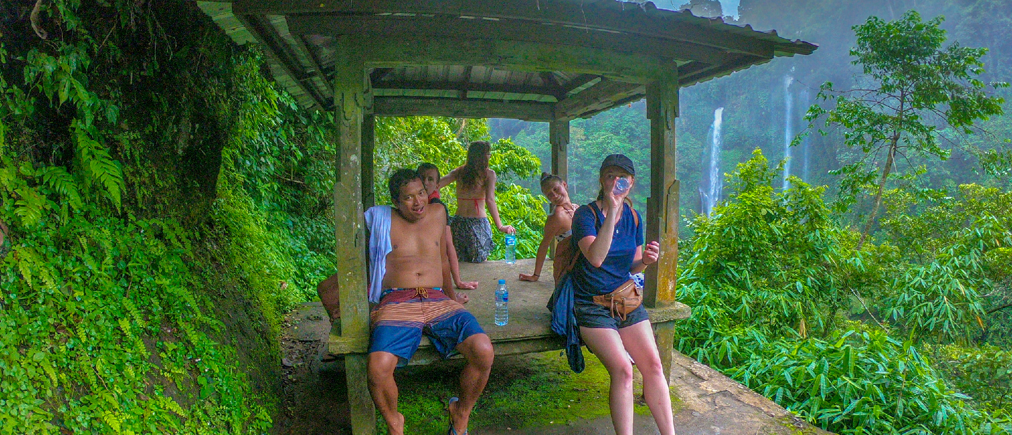 Two travellers resting at a small shelter by rice terraces