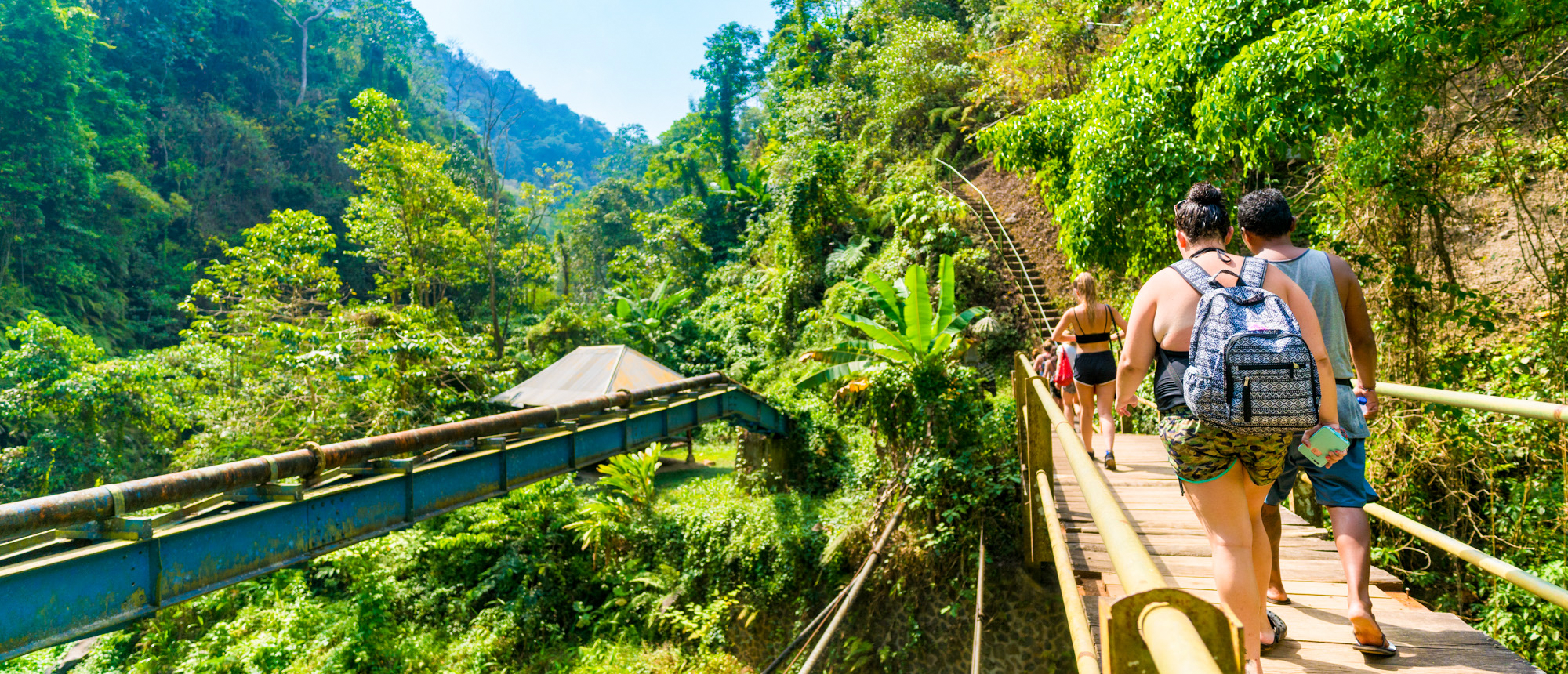 Travellers crossing a wooden suspension bridge over a river