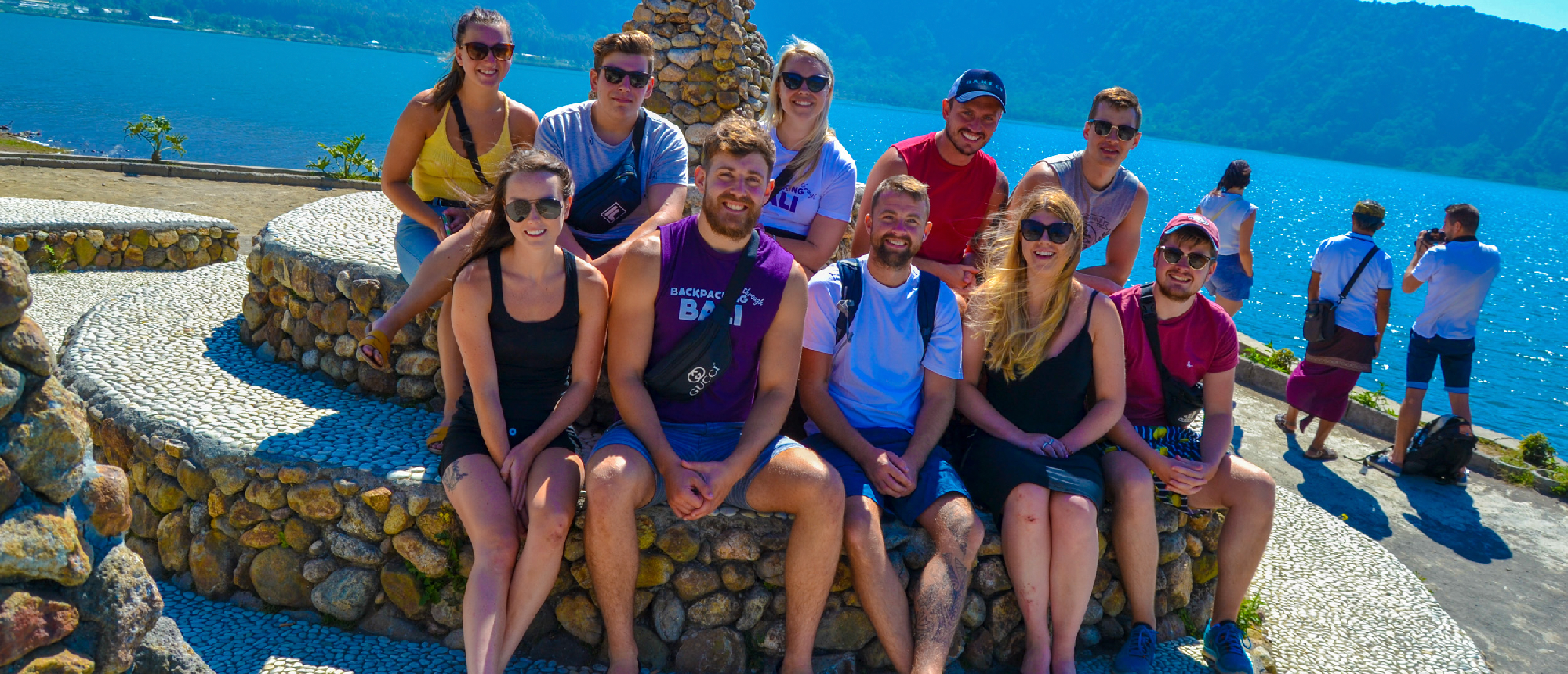 Group relaxing by a pool at a beach club with an ocean backdrop