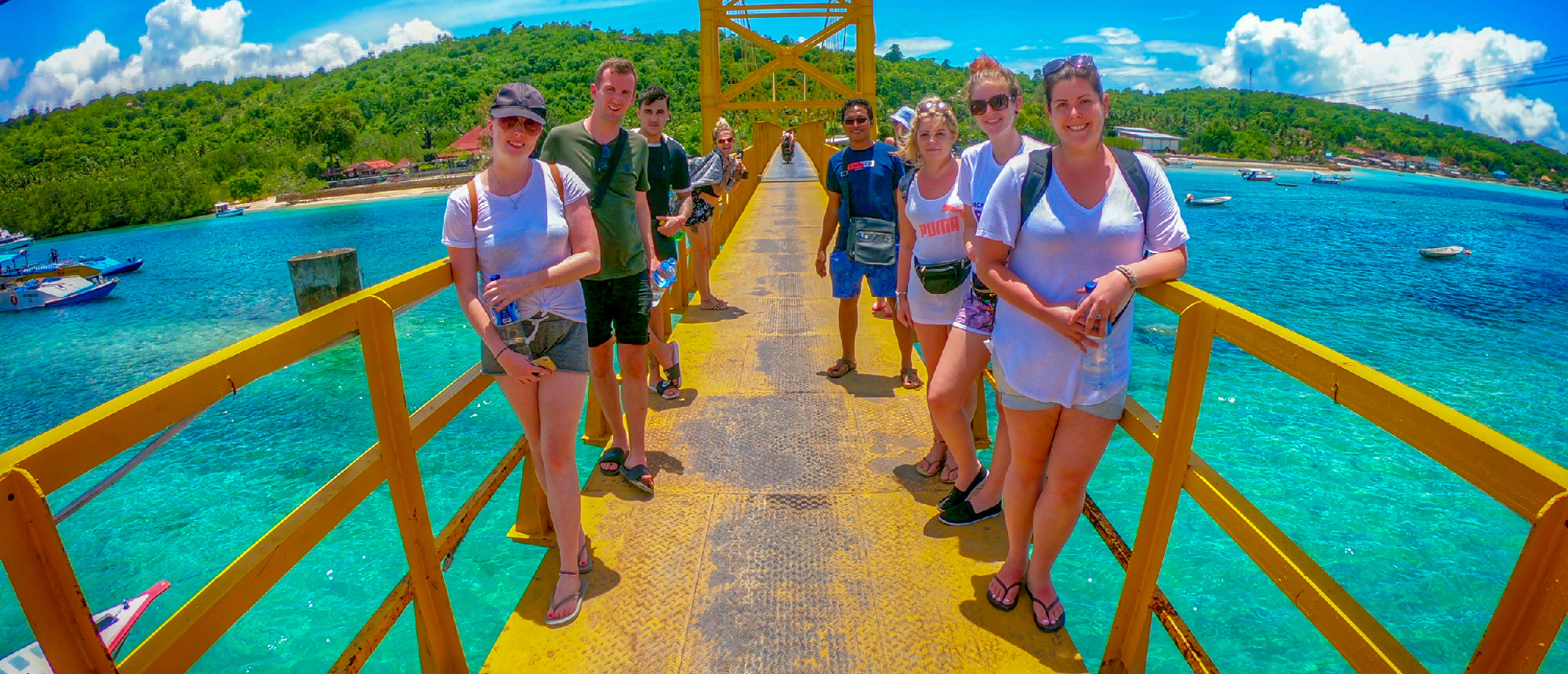 Backpacking group crossing the Yellow Bridge in Nusa Lembongan