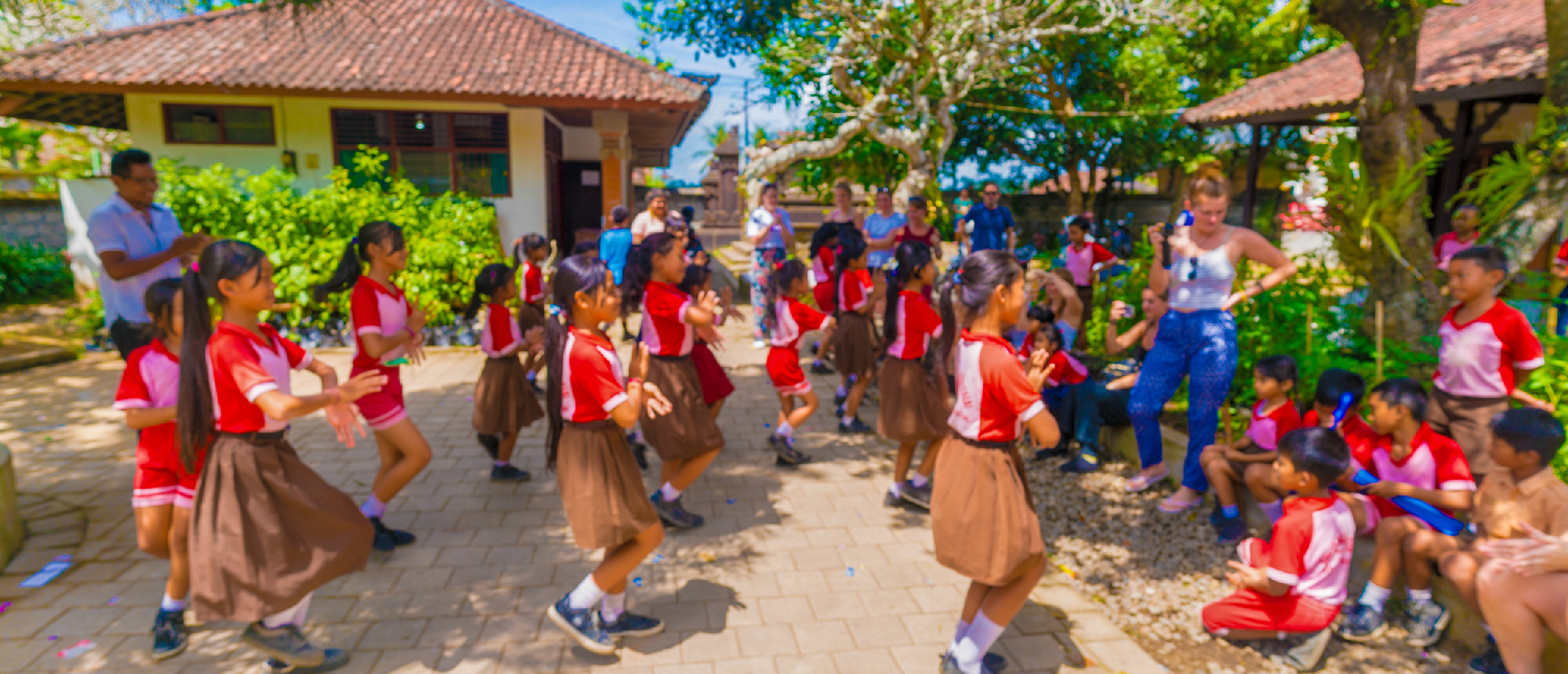 Backpacking group interacting with local students at a school in Ubud