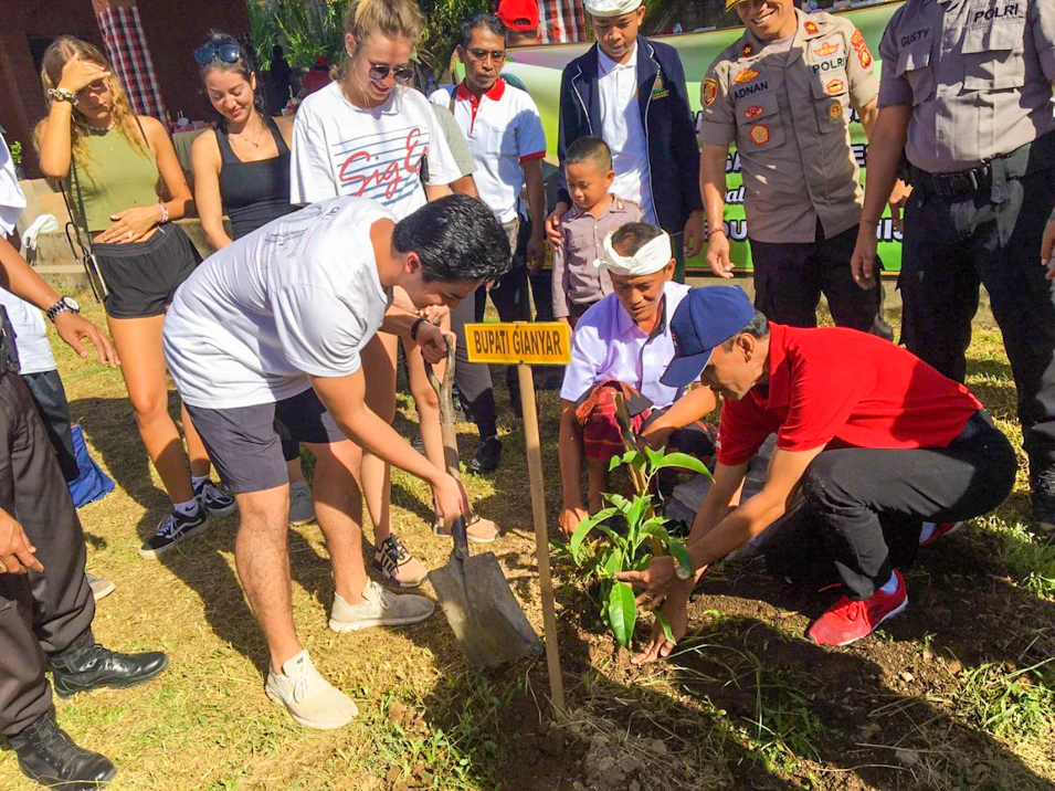 Tourists and locals planting a tree together during an environmental education program in Bali.