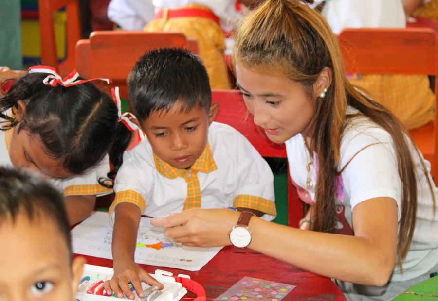 A female volunteer helps a young boy with his schoolwork at a kindergarten in Bali.