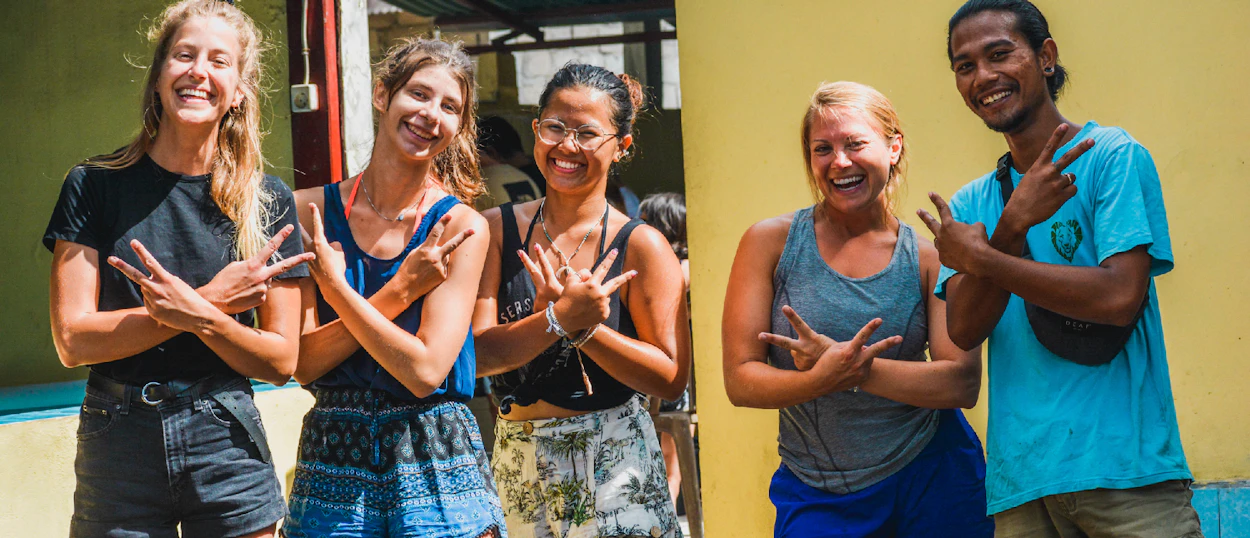 Five happy travelers and a local guide making hand gestures in Nusa Penida, Bali.