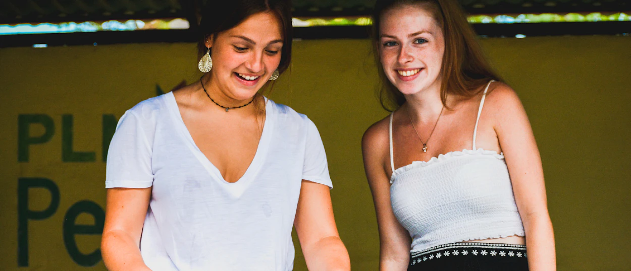Two smiling young women volunteering at a turtle conservation project in Nusa Penida, Bali.