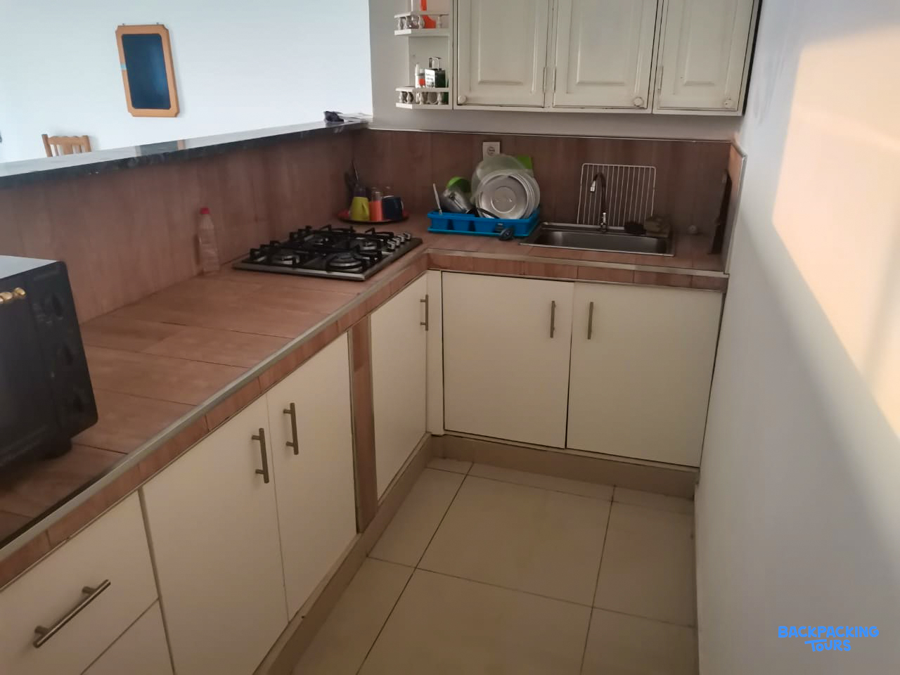 A clean and practical kitchen in the accommodation, featuring a gas stove, white cabinets, and tiled counters.