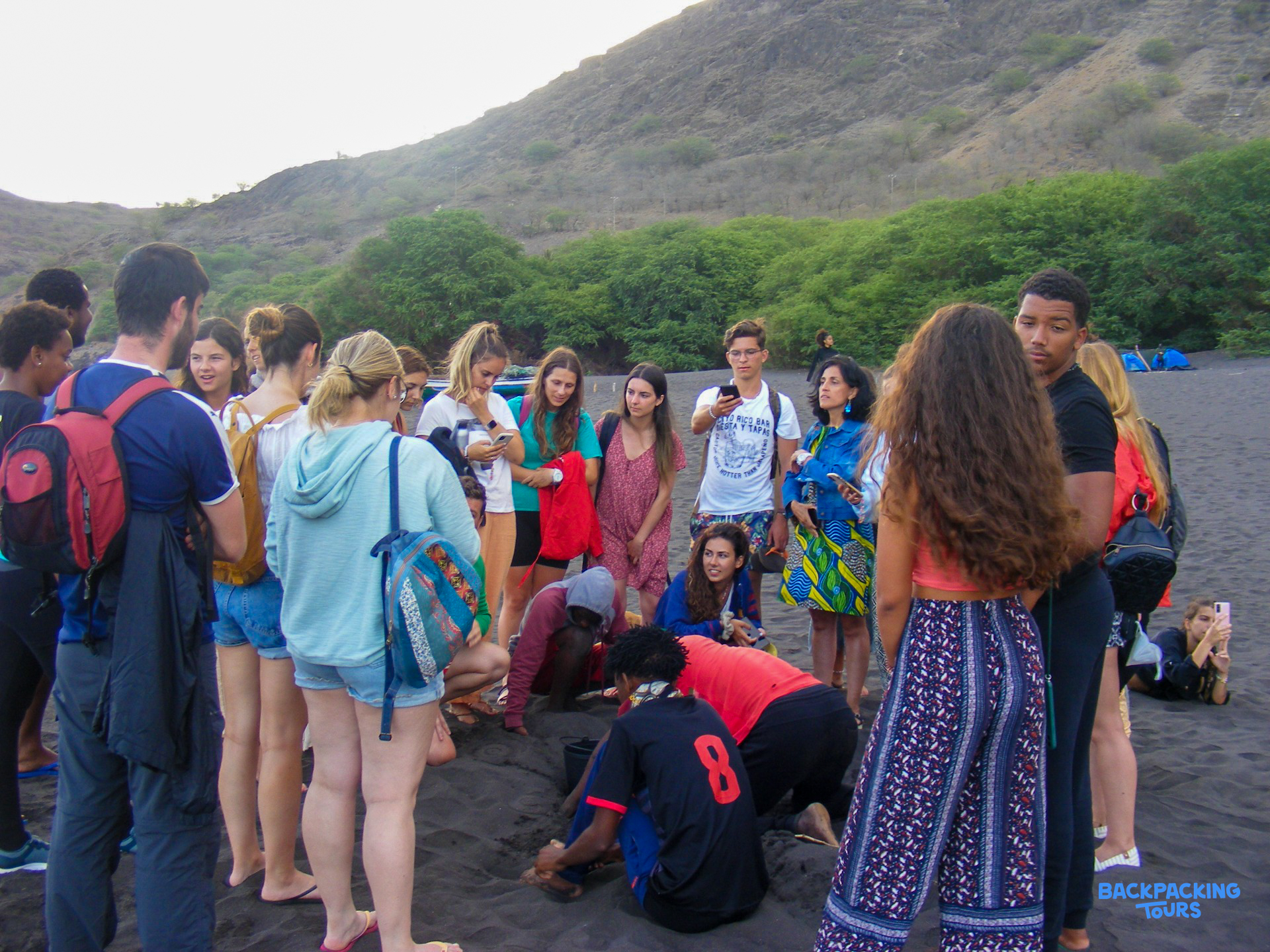 Young volunteers on a dark beach in Cape Verde, carefully searching for turtle eggs.