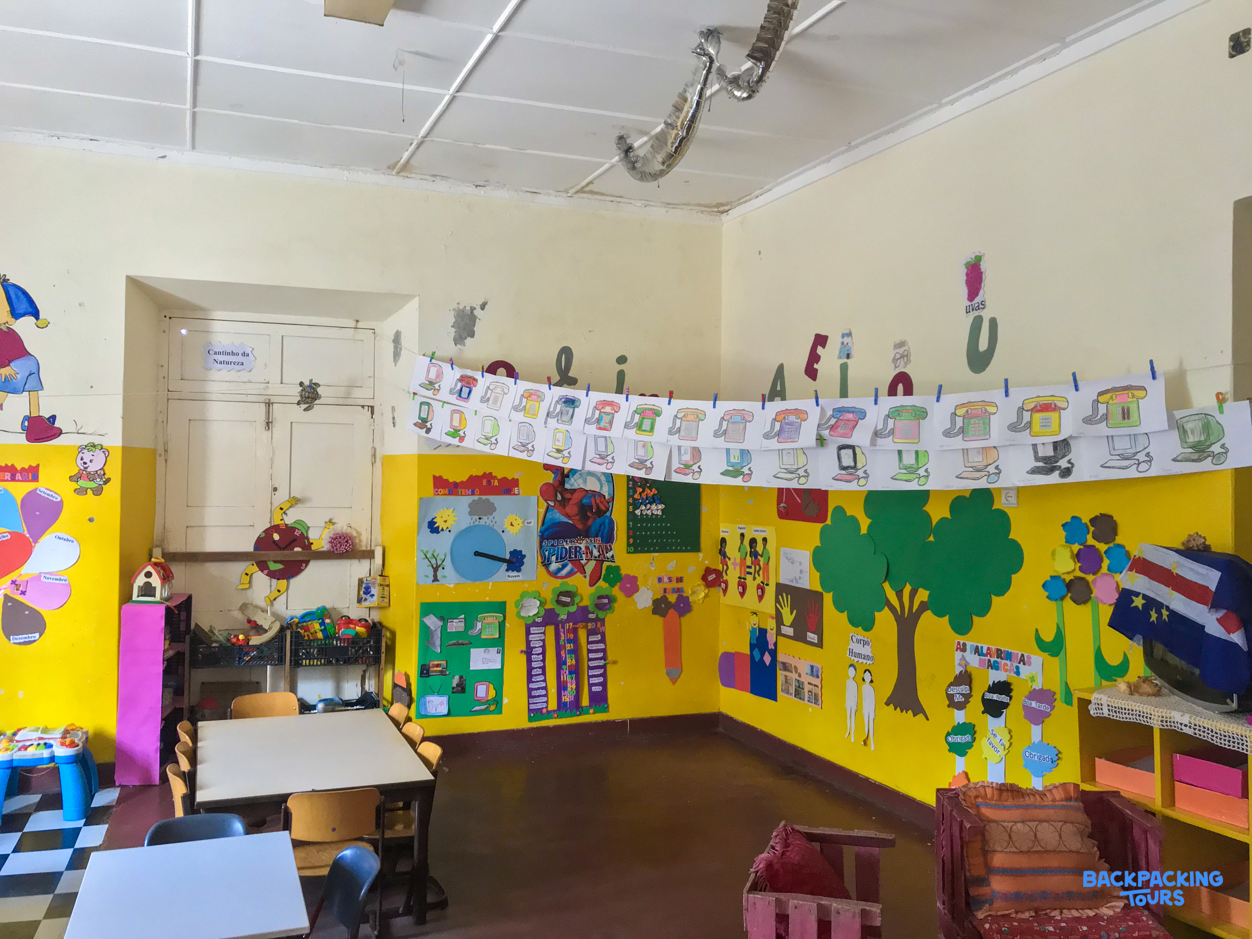 A brightly decorated classroom with yellow walls and children's artwork, an inviting learning space in Cape Verde.