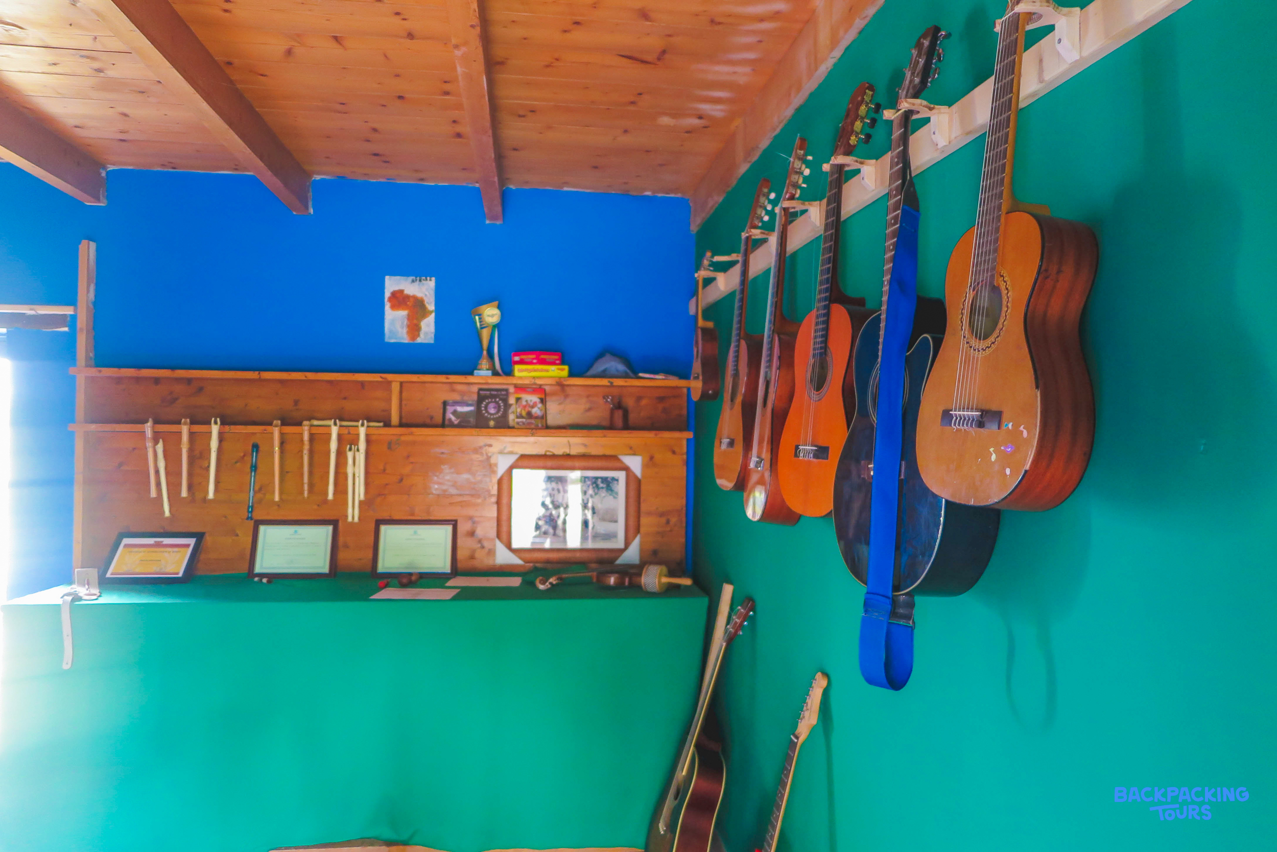 A bright room with blue and green walls, featuring multiple acoustic guitars and musical instruments.