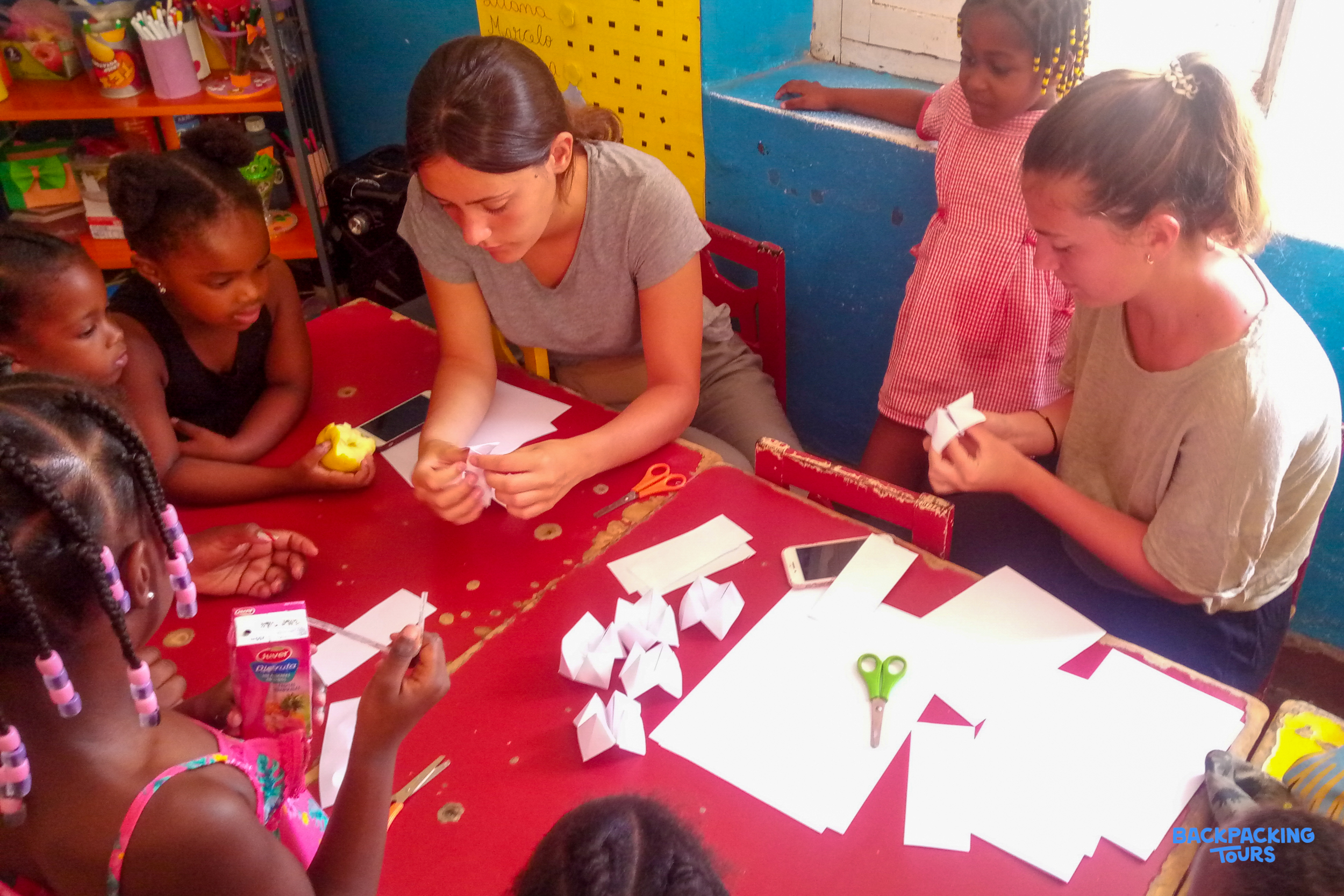 Volunteers and children happily engage in a paper craft activity at a community center.