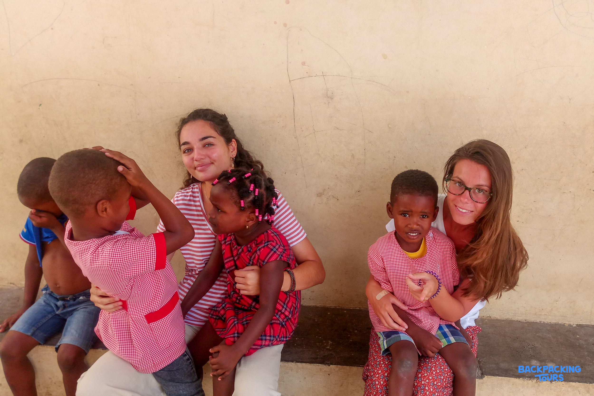 Two smiling women happily interact with four young children, creating a warm and joyful scene.