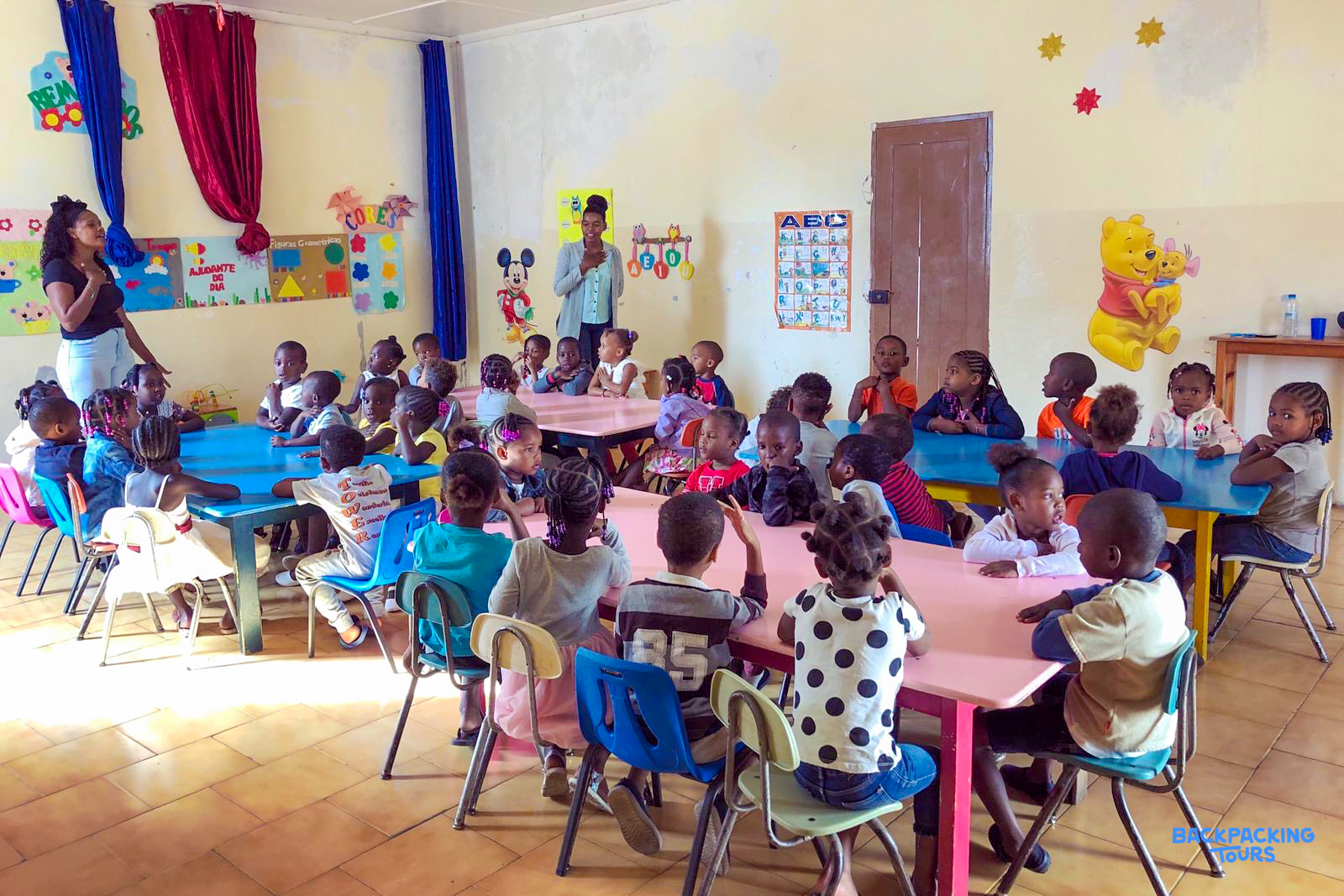 Young children in a brightly decorated classroom in Cape Verde, engaged in learning activities.