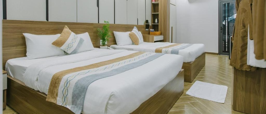 Two double beds with white linen and patterned runners in a bright room with wooden headboards.