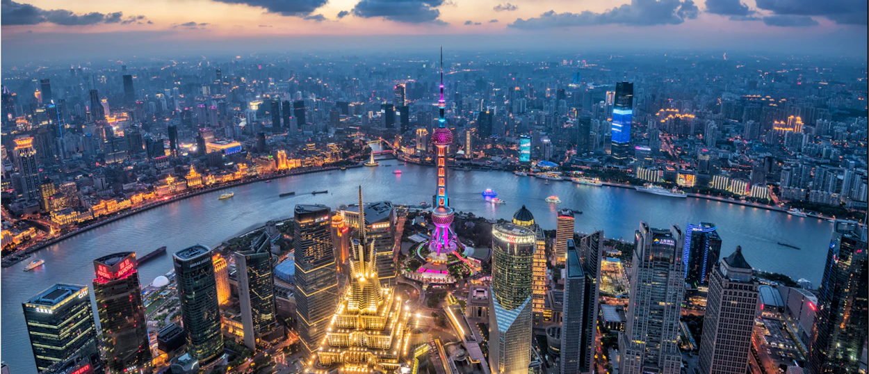 Shanghai's dazzling city lights illuminate the Huangpu River and iconic skyscrapers at twilight.