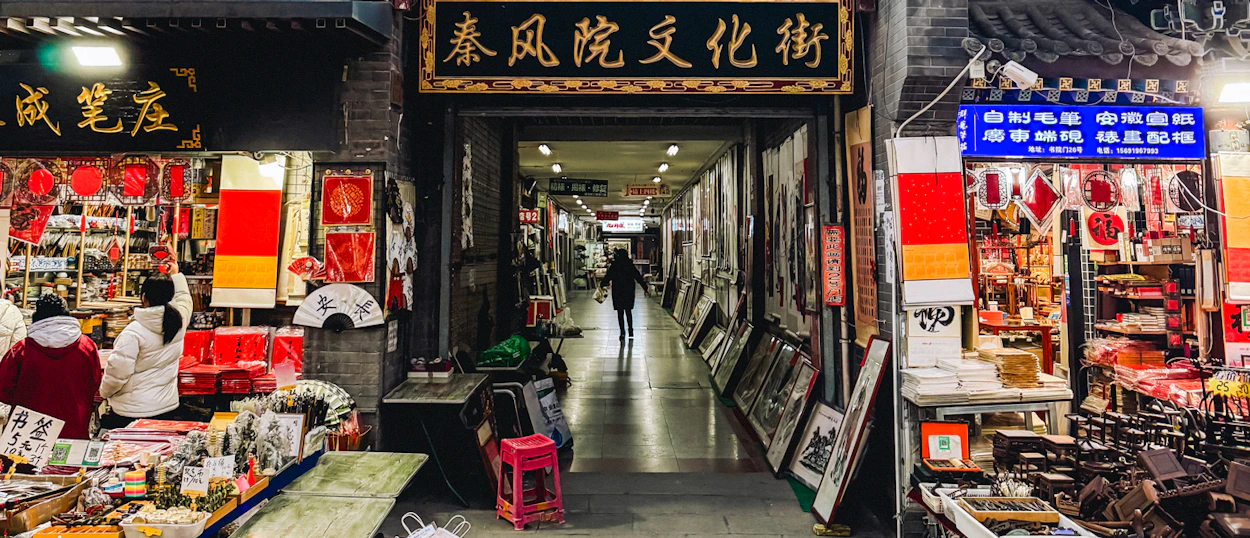 People browse vibrant stalls selling traditional Chinese crafts and art in a Xi'an cultural street.