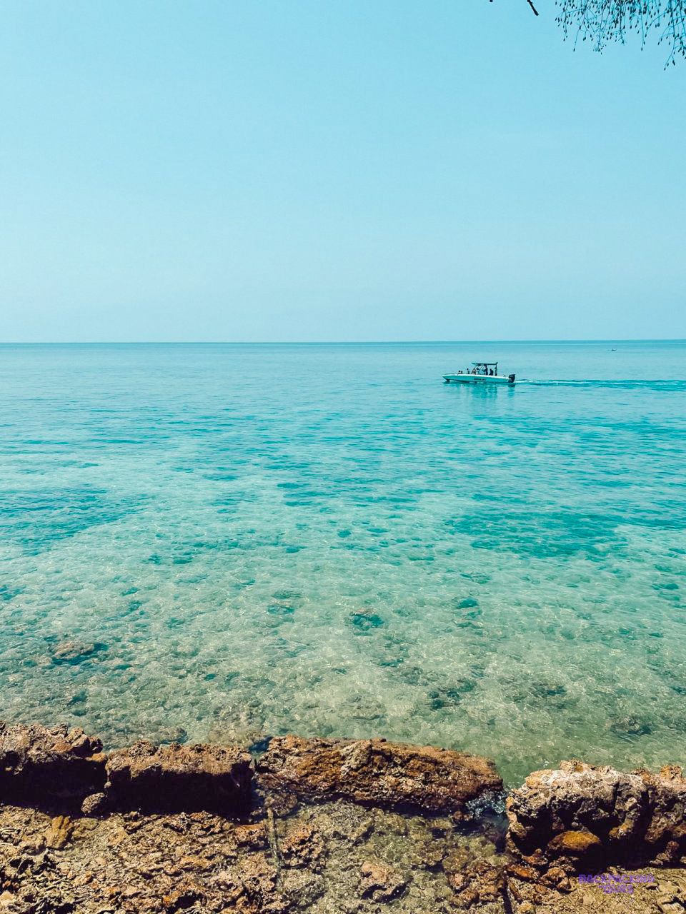 Clear turquoise water over a rocky seabed at Islas del Rosario, with a boat in the distance