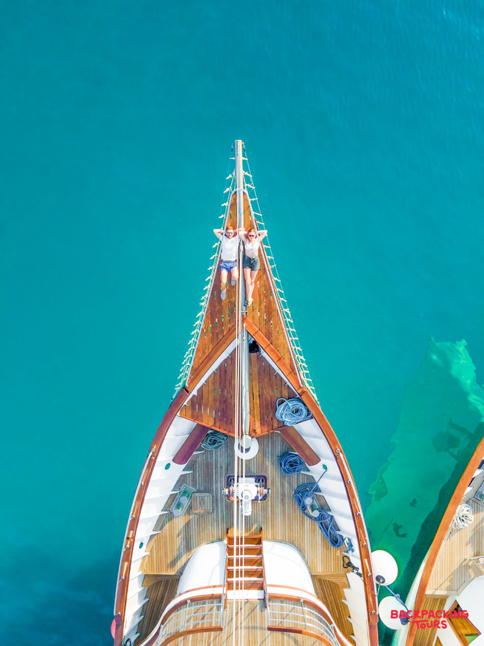 Two people relaxing on a sailing boat, sunbathing in the clear turquoise waters of Makarska.