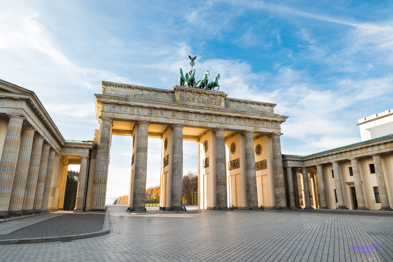 The Brandenburg Gate in Berlin, its columns and chariot statue lit by a low sun.