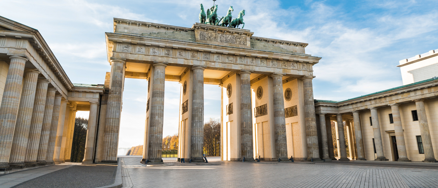 The Brandenburg Gate in Berlin, its columns and chariot statue lit by a low sun.