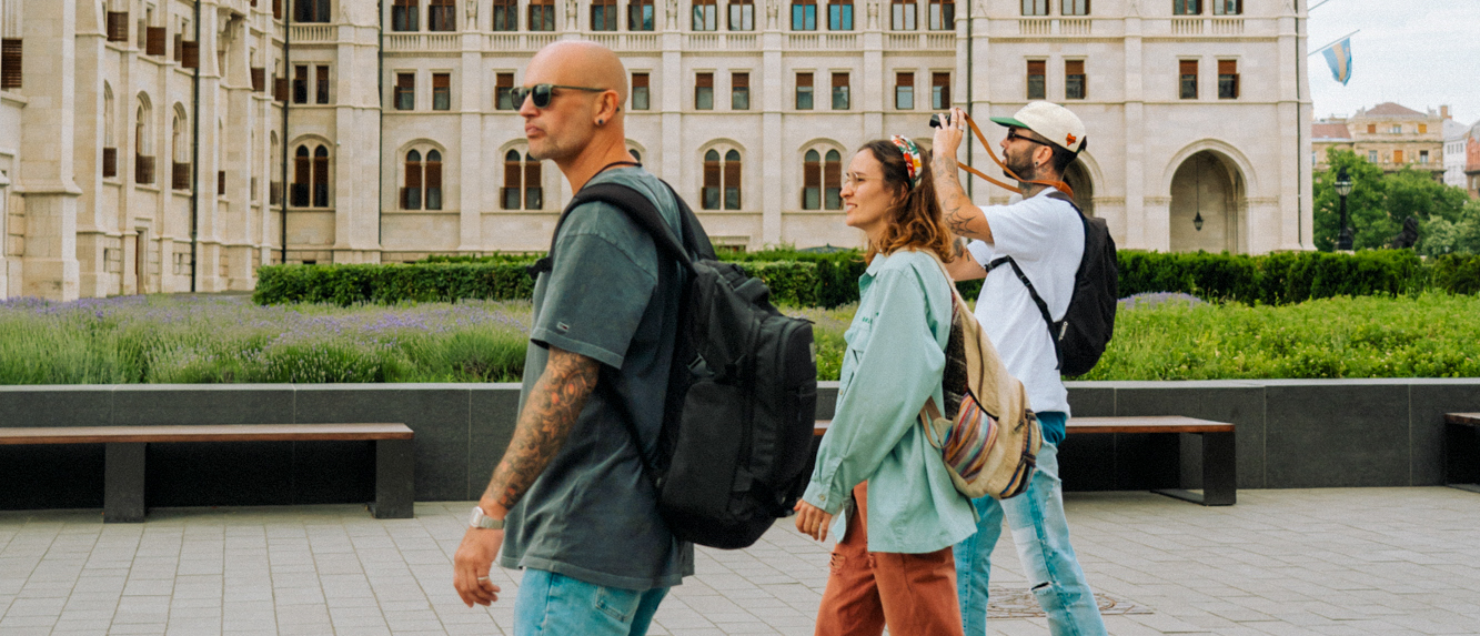 Three travellers with backpacks walk past the Hungarian Parliament building in Budapest.