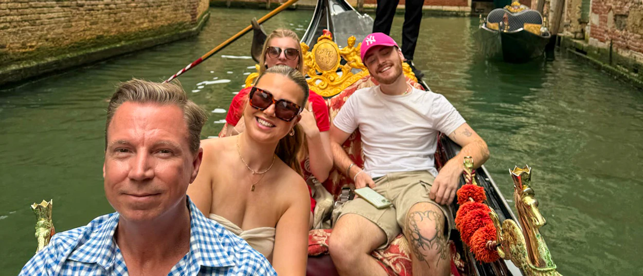 Four happy travelers enjoy a scenic gondola ride through the canals of Venice.