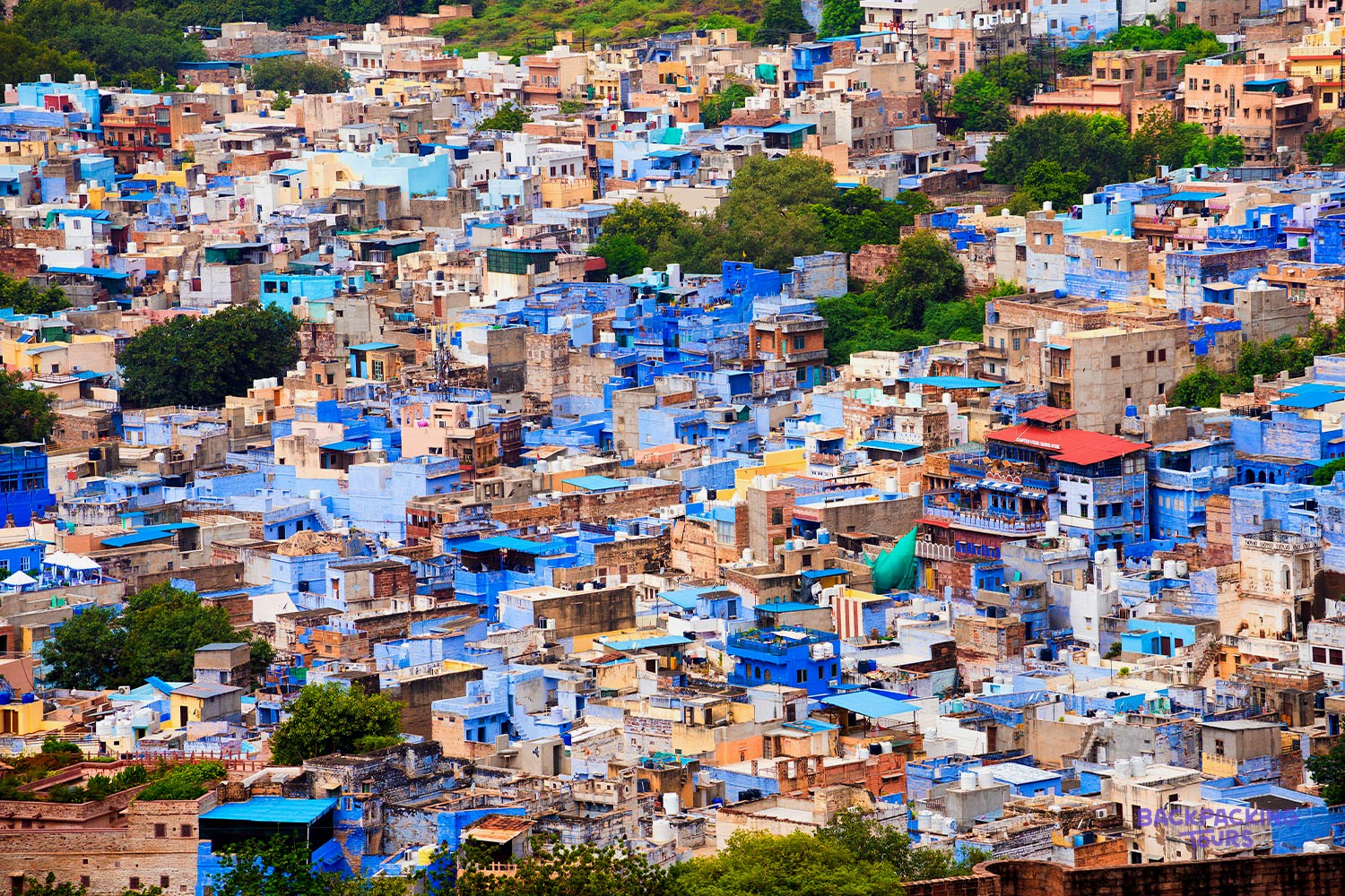 Numerous blue and pastel-coloured buildings with flat roofs cover a hillside.