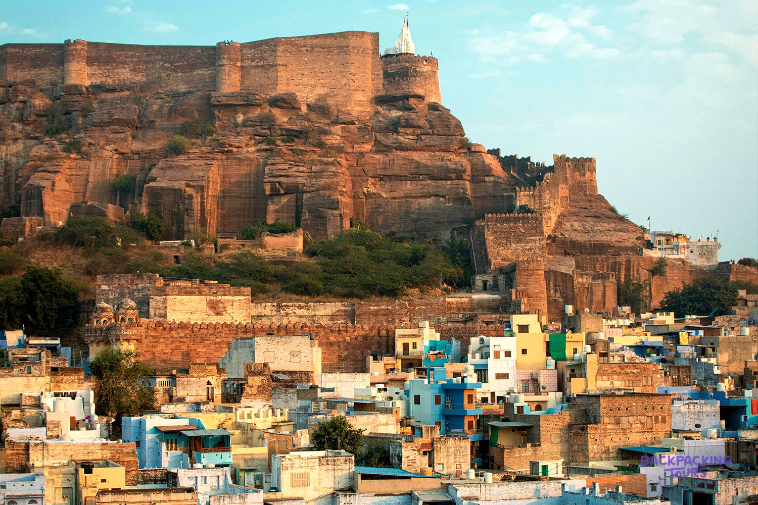 A massive stone fort with a white spire overlooks a city of blue and light-coloured buildings.