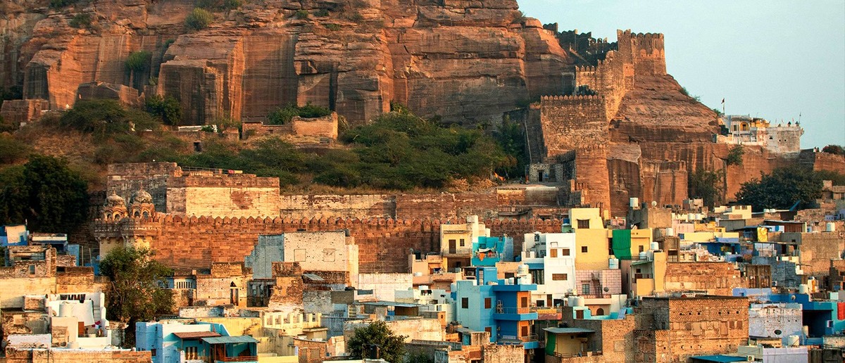 A massive stone fort with a white spire overlooks a city of blue and light-coloured buildings.