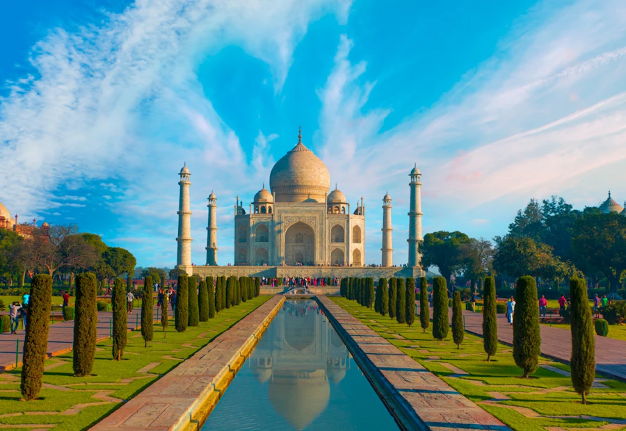 The majestic Taj Mahal in India, reflected beautifully in a long pool under a blue sky.