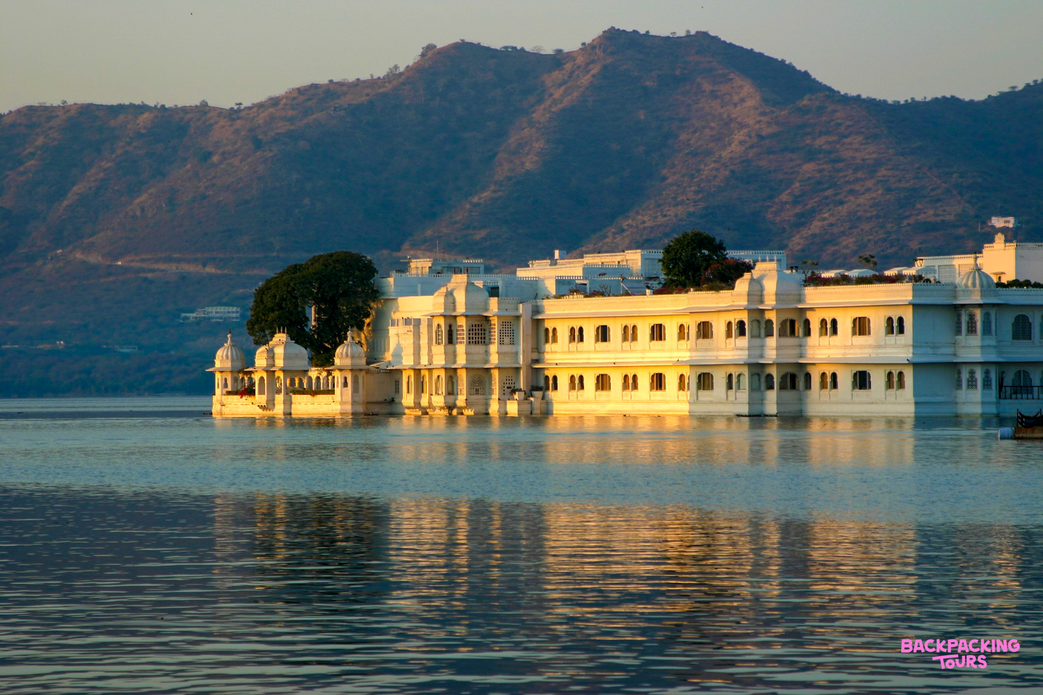 A majestic white palace on Lake Pichola in Udaipur bathed in the warm glow of sunset.