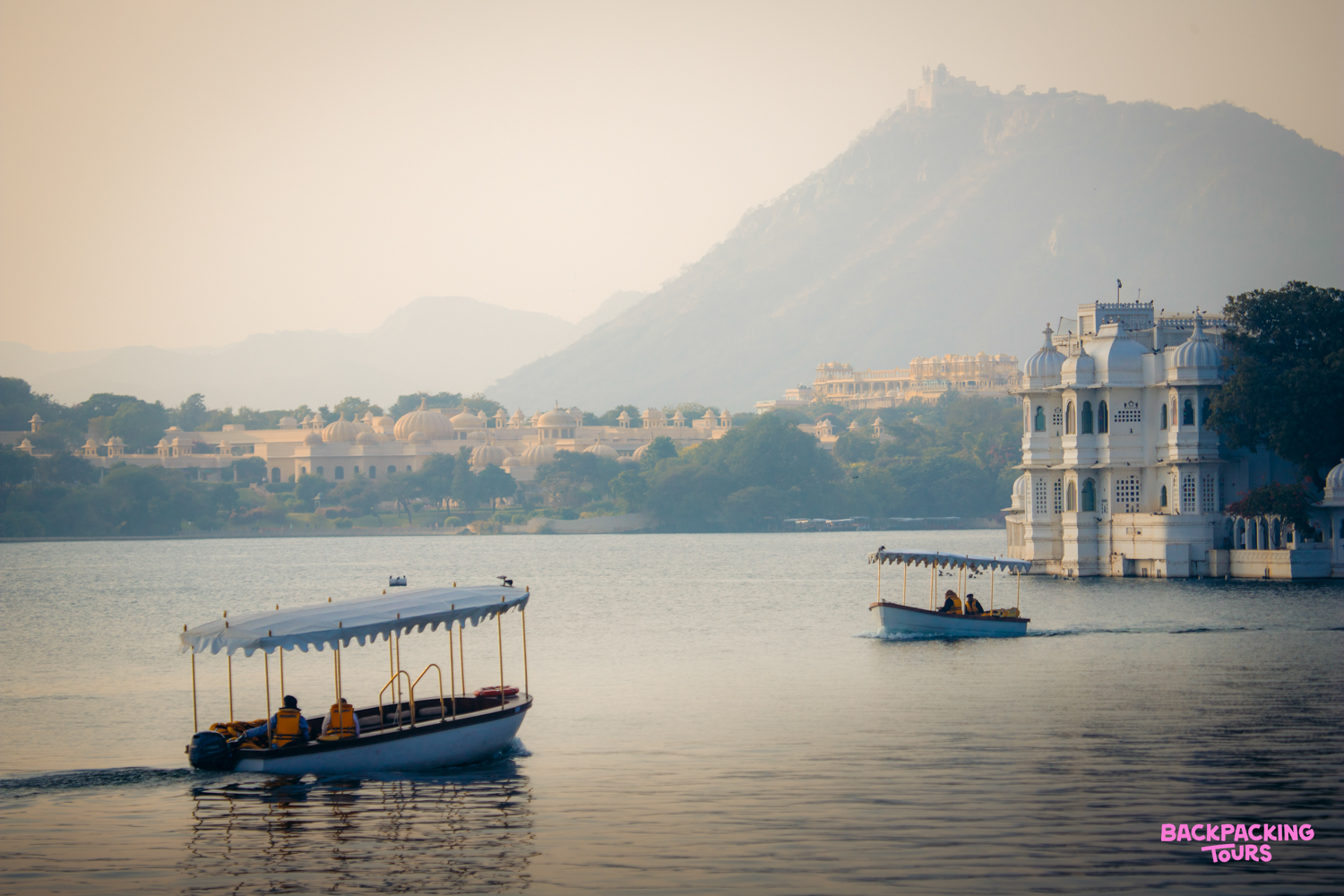 Enjoying a serene sunset boat cruise on Lake Pichola, with palaces and mountains in Udaipur.