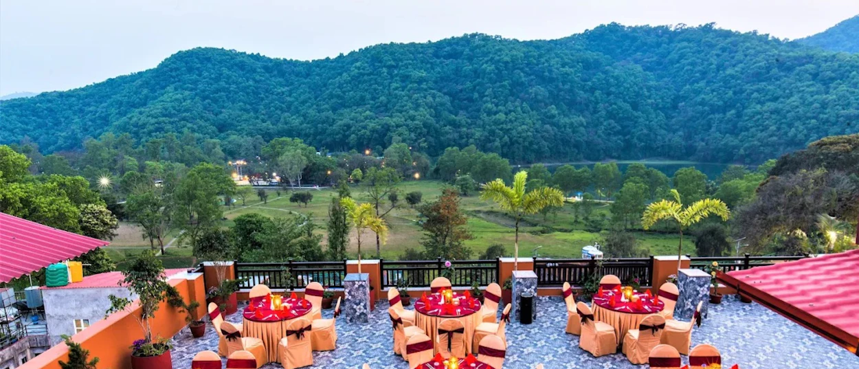 Outdoor terrace with elegant tables and chairs overlooking lush green mountains at Australian Camp.