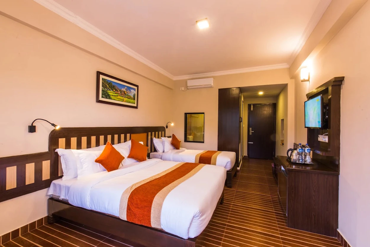 Comfortable hotel room in Pokhara featuring two beds, white linens, and warm wooden furnishings.