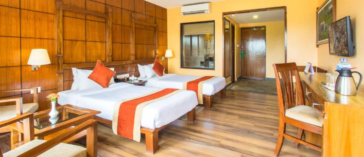 Cozy lodge room with two beds, wooden walls, a desk, and a sitting area.