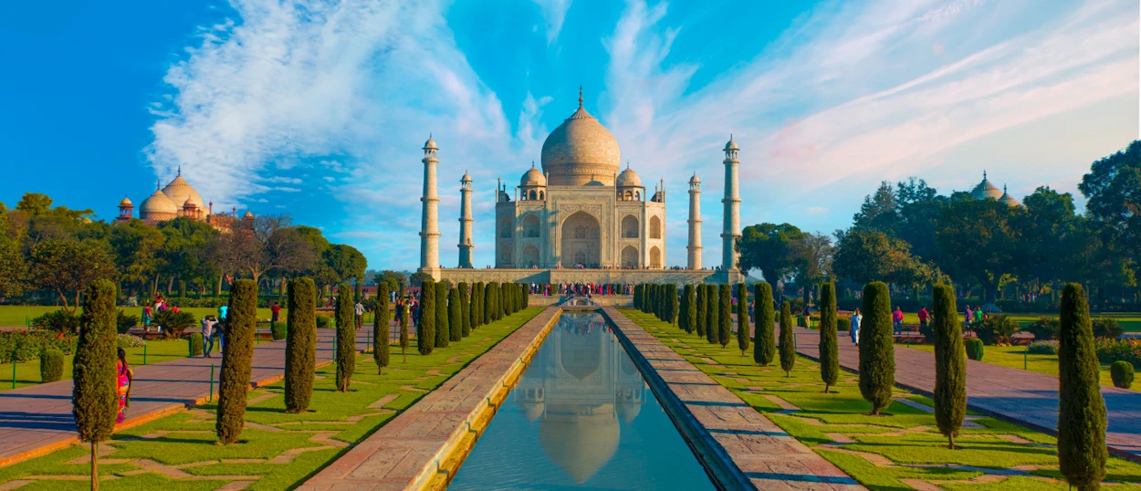 The majestic Taj Mahal in Agra, India, with its reflecting pool and manicured gardens under a blue sky.