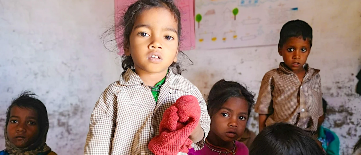 Young Indian children look curiously at the camera in a simple room in Udaipur.