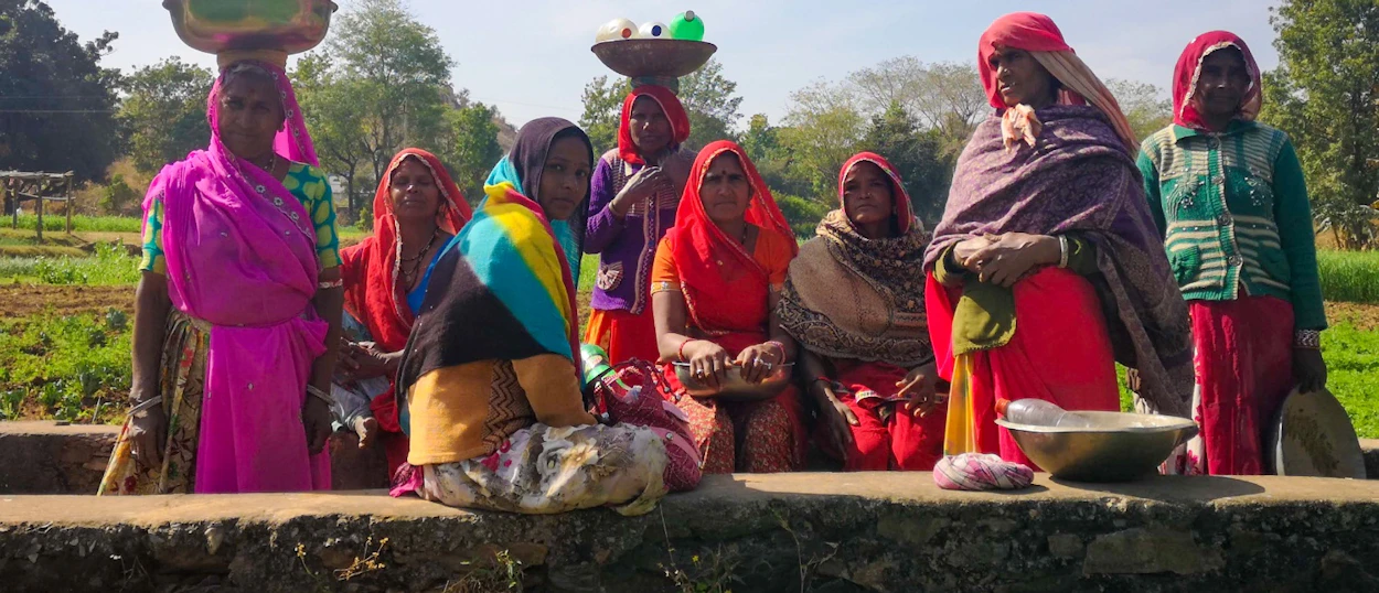 Local women in vibrant traditional Indian attire gather in Udaipur, some with baskets on their heads.