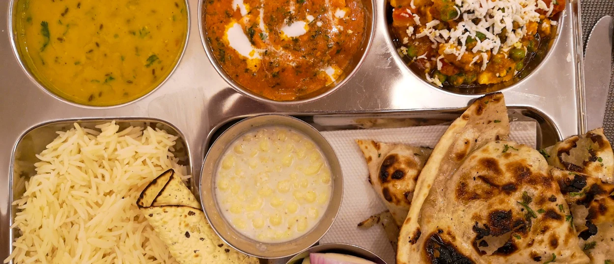 A vibrant North Indian thali meal featuring rice, various curries, raita, and naan bread in Udaipur.