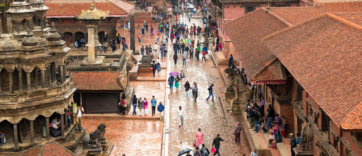 Crowds of people fill a historic Kathmandu Durbar Square, surrounded by traditional tiered temples.