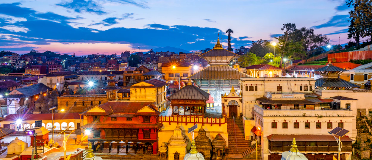 Traditional temples and buildings glow under a twilight sky in Kathmandu, Nepal.