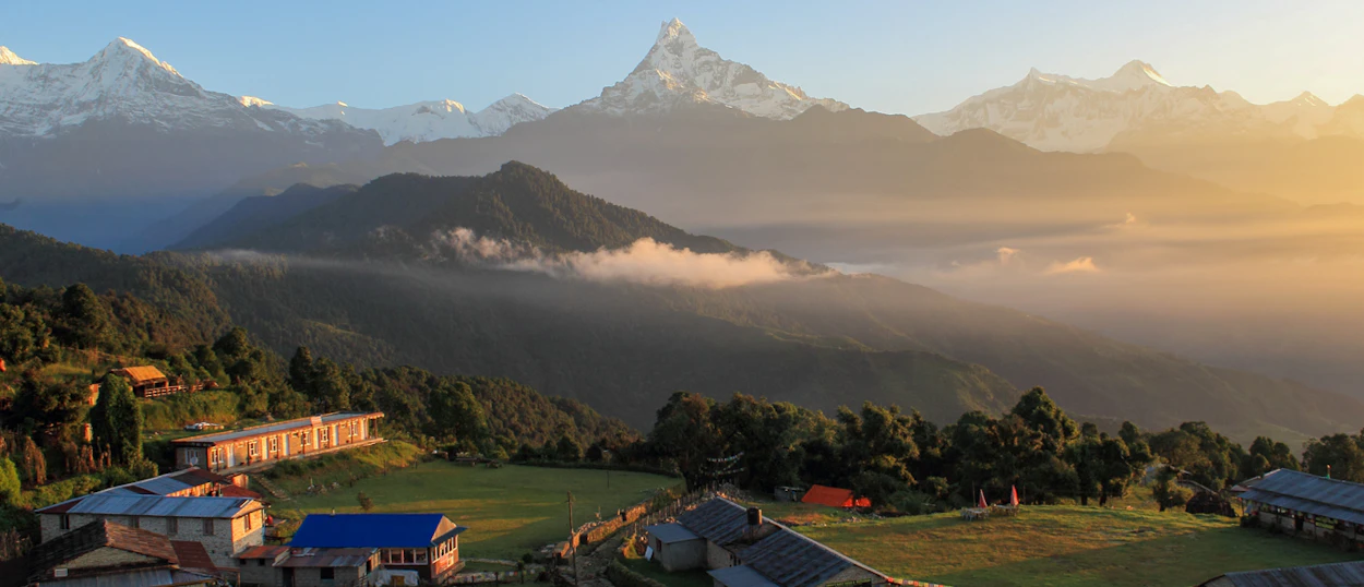 Majestic Annapurna mountains tower over Australian Camp at sunrise, with golden light on misty valleys.