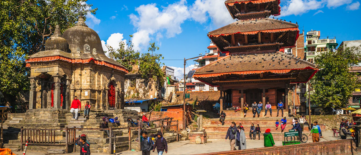 Crowds of people explore ancient temples and historic buildings in Kathmandu's vibrant square.