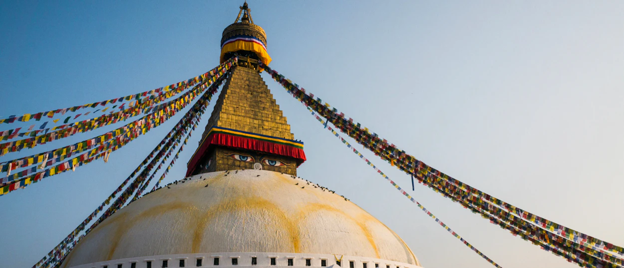 Colorful prayer flags stream from the golden spire of the majestic Swoyambhunath Stupa in Kathmandu.
