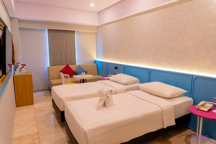 A twin room with white beds and a blue padded wall at the hotel in Canggu