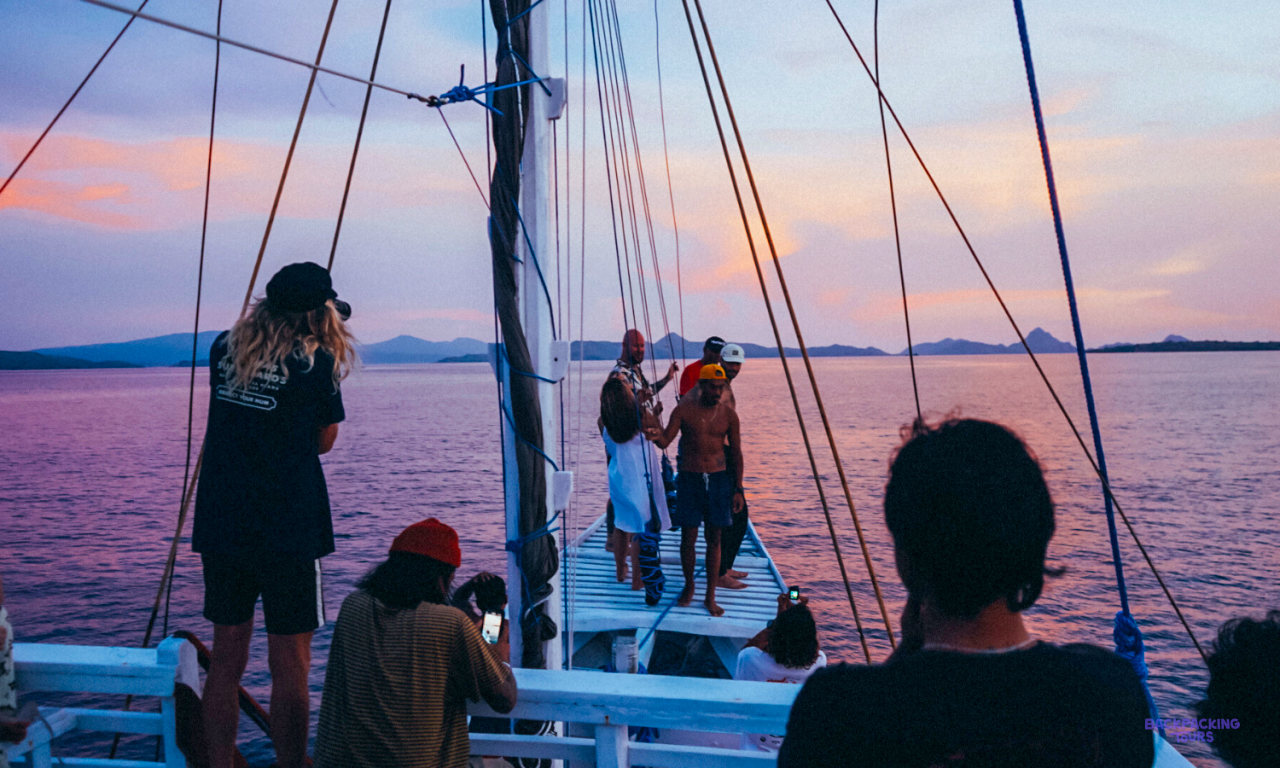 Travellers taking photos from the deck of the liveaboard boat at sunset