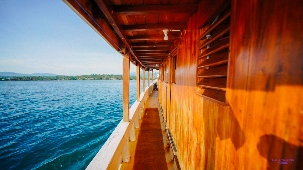 The wooden side deck of the liveaboard boat above calm blue water