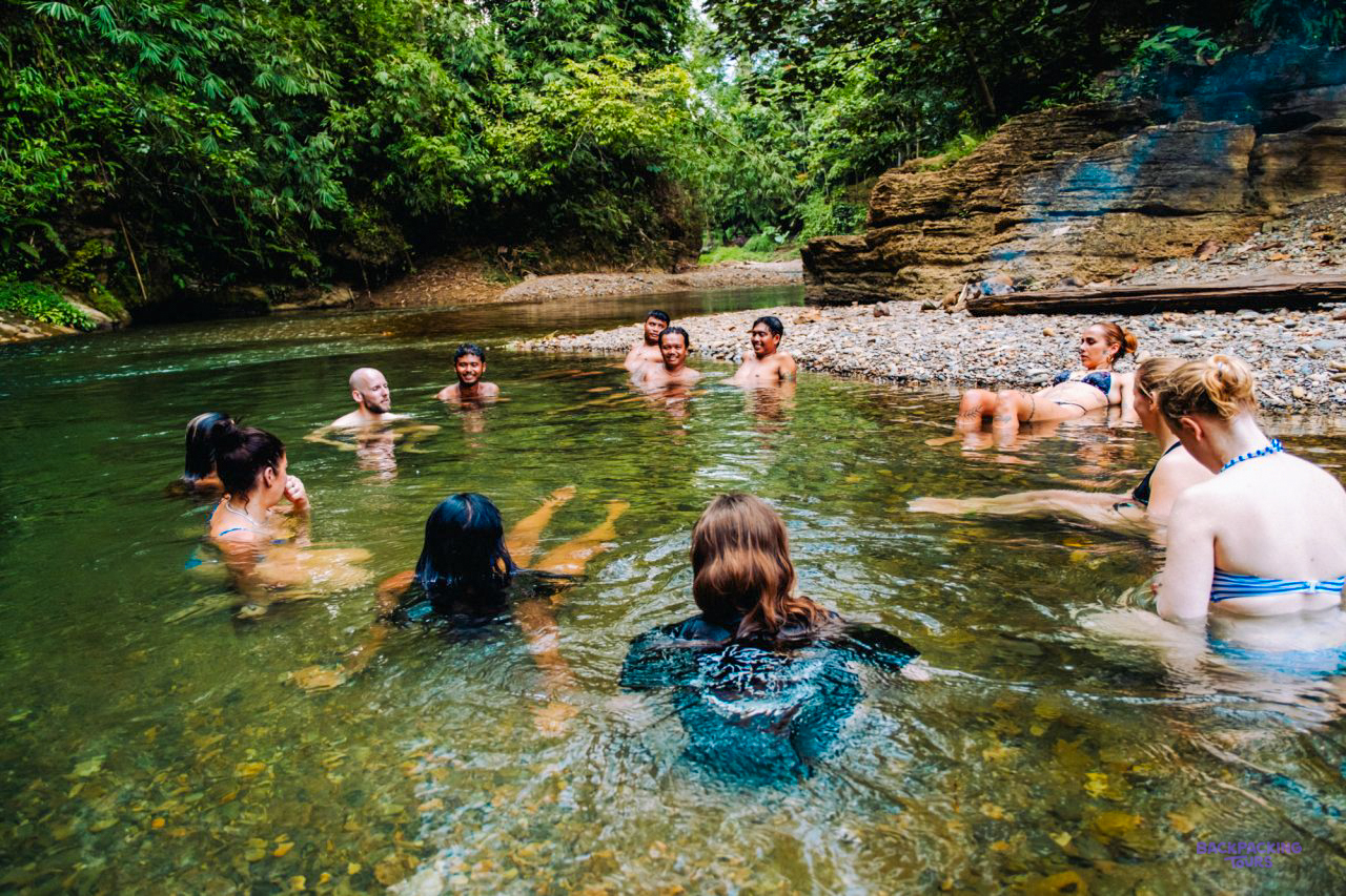 Travellers cooling off in a jungle river on the water trek in the Mentawai Islands
